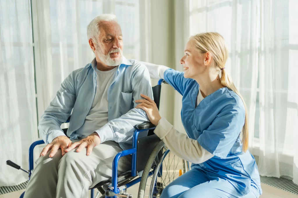 Díky očkování můžete předejít zdravotním komplikacím. Zdroj: Shutterstock - ByznysDeník Zdravotní sestřička, která sedí u staršího muže na vozíku.