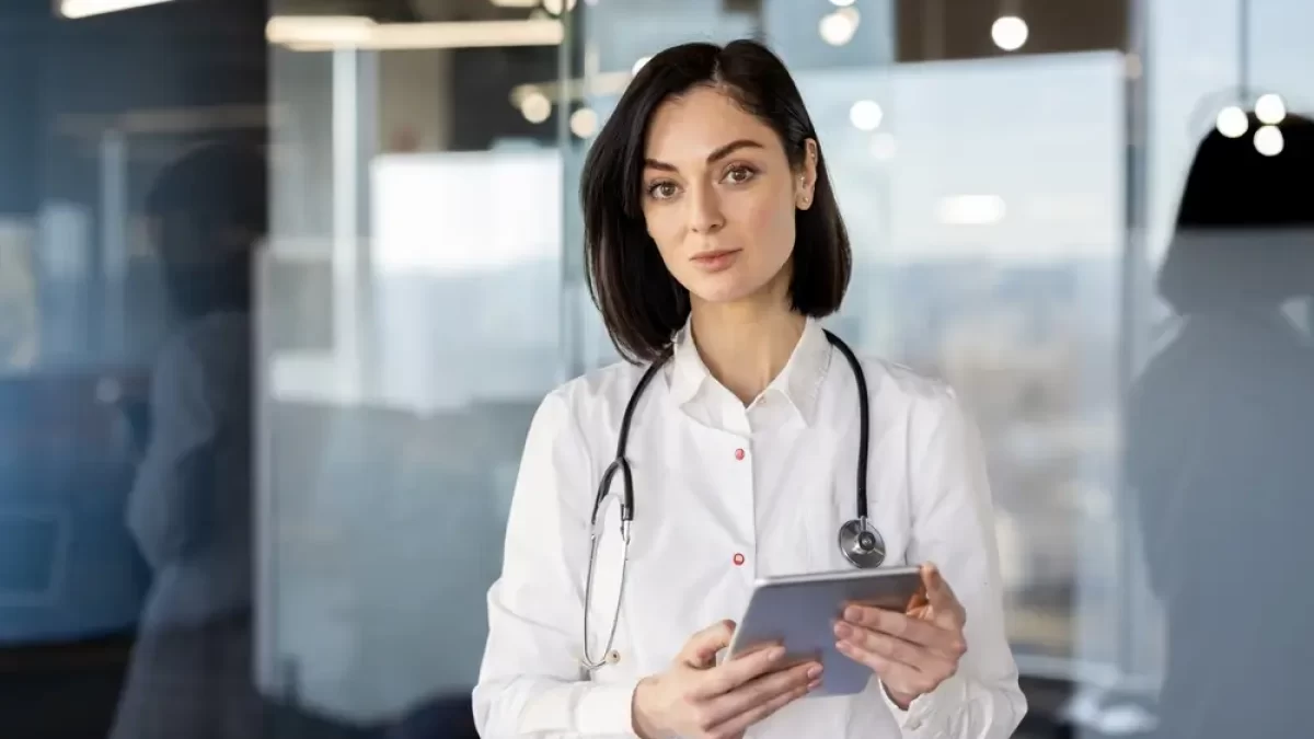 Lékařka drží v ruce tablet.