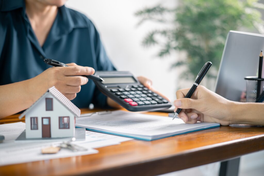 I přes klesající úrokové sazby je stále pro mnohé vlastní bydlení nedostupné, Zdroj: Shutterstock.com - ByznysDeník Finanční poradce vypočítává splátky na hypotéku klientovi a ukazuje mu kalkulačku