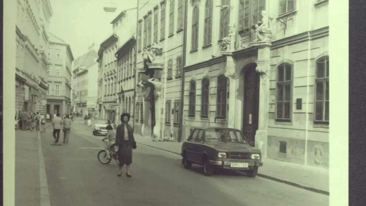 Žena procházející v ulici kolem auta v roce 1980.