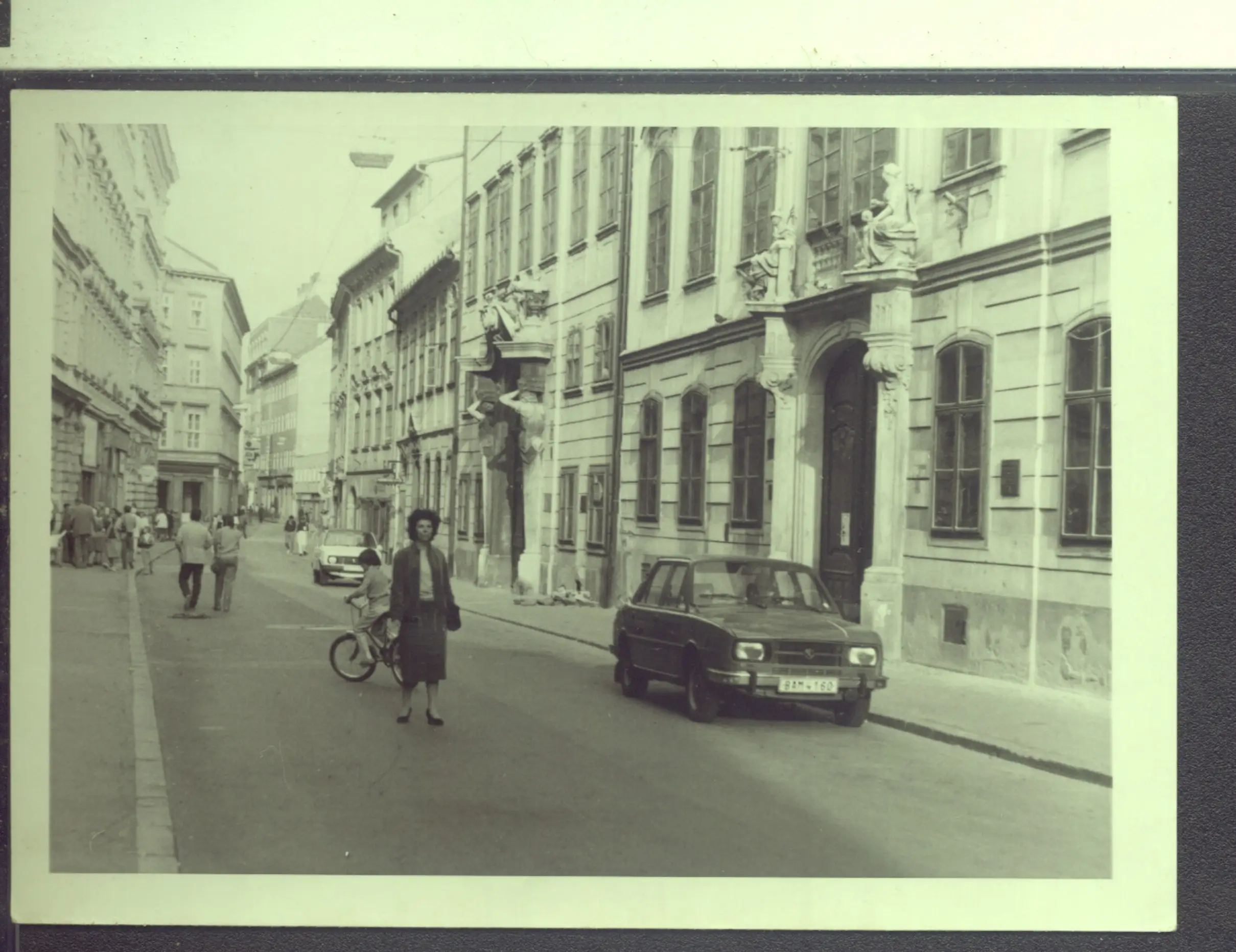 Žena procházející v ulici kolem auta v roce 1980.