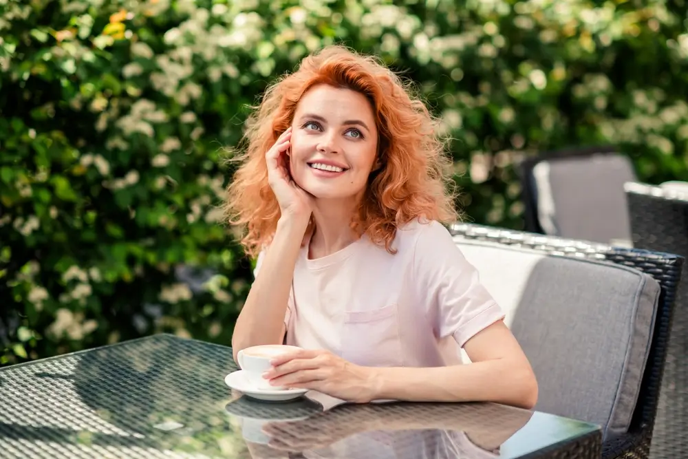 shutterstock_2599832553 - ByznysDeník Žena se zasněně usmívá a hledí do prázdna.