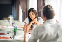 Žena sedí naproti muži v restauraci a podezřívavě se na něj dívá.