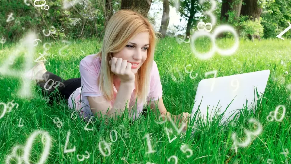 Žena leží v trávě s notebookem. Okolo ní jsou čísla.