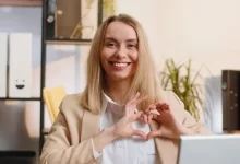 Žena tvaruje srdce z prstů a dlaní.