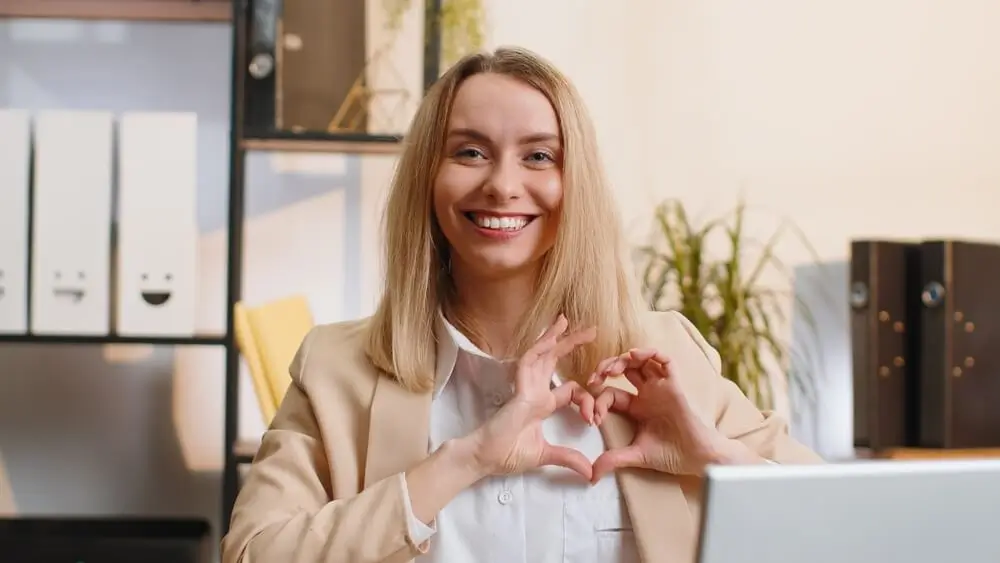 Žena tvaruje srdce z prstů a dlaní.