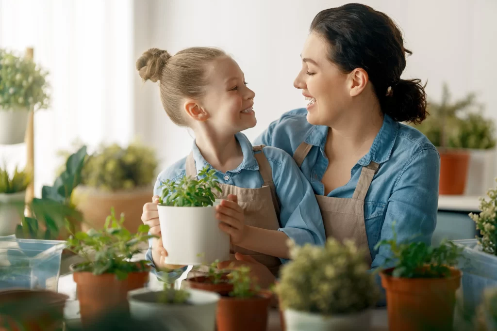 Péče pokojovky nemusí být nijak náročná. Zdroj: Shutterstock - ByznysDeník Žena s dcerou pečující o květiny v květináči.