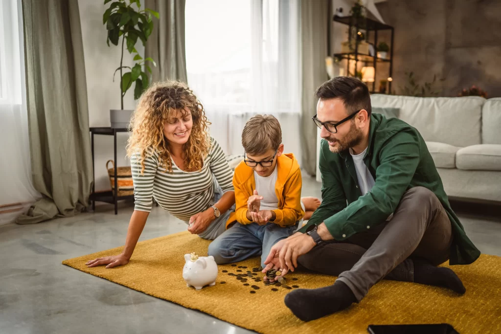 Přes léto přemýšlejte, kam peníze vhodně investovat. Zdroj: Shutterstock - ByznysDeník Rodiče s dítětem rozdělující peníze.