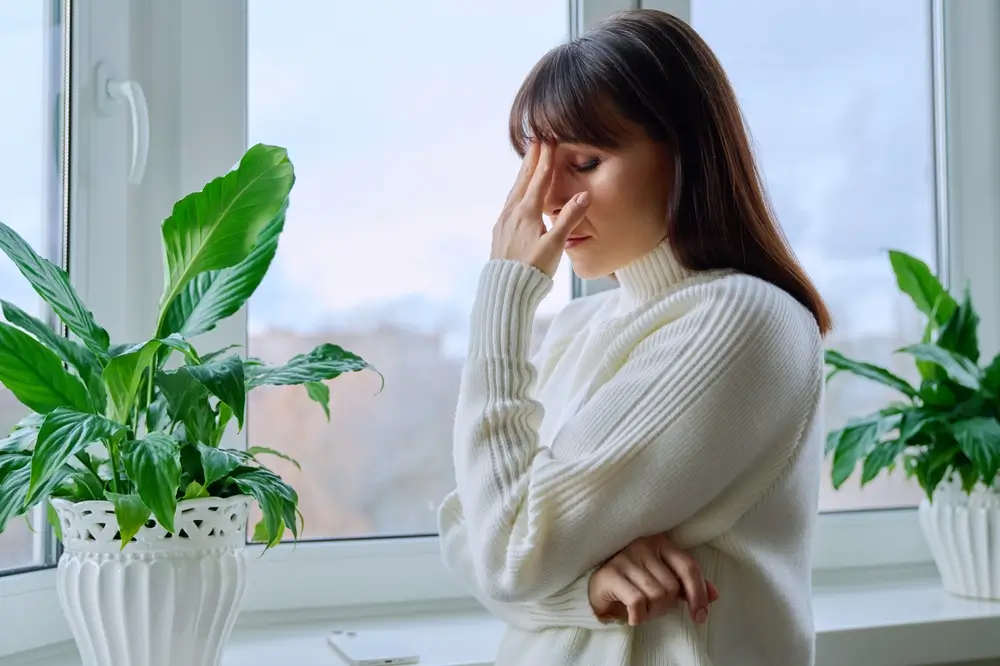 Žena u okna se chytá za hlavu.