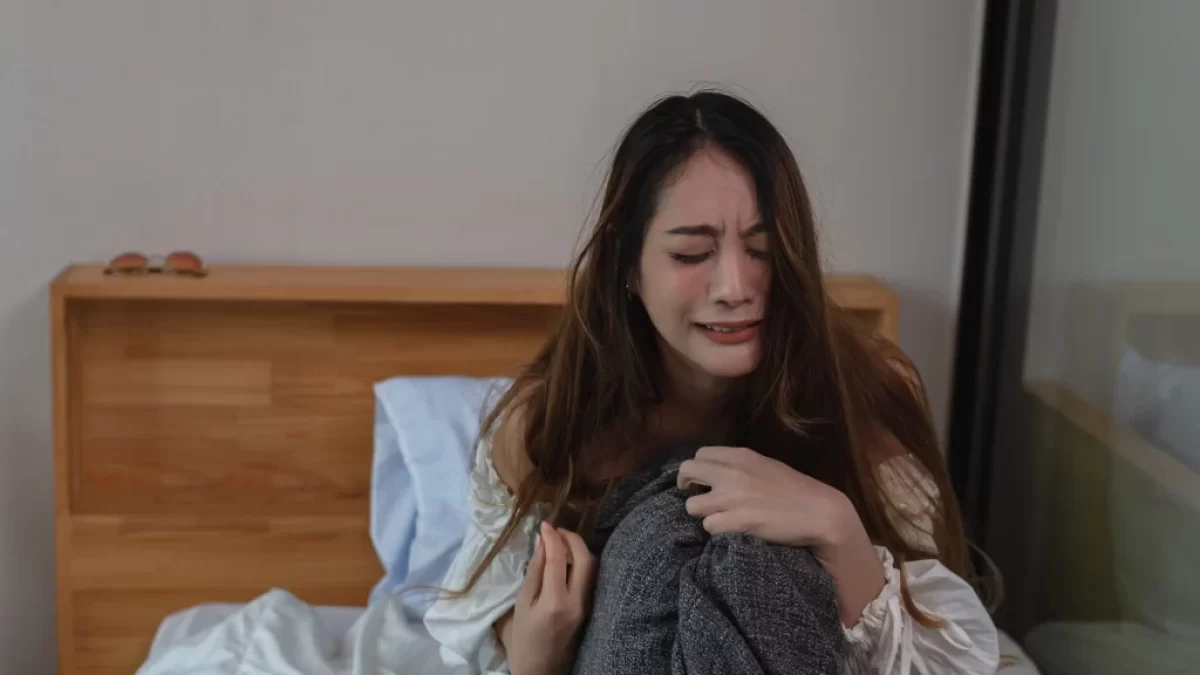 Plačící žena na posteli.