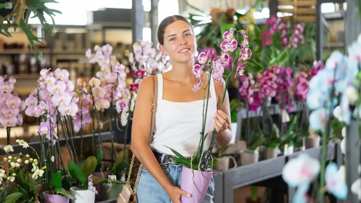 Žena drží v ruce orchidej.