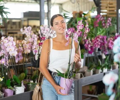 Žena drží v ruce orchidej.