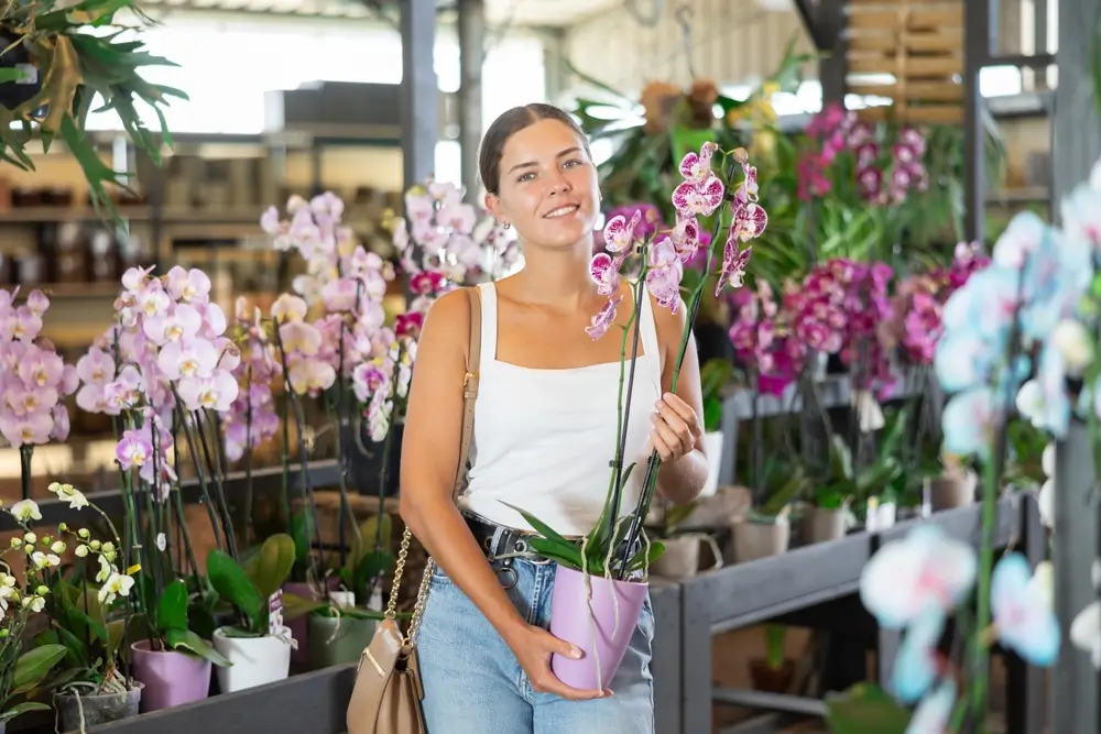Žena drží v ruce orchidej.