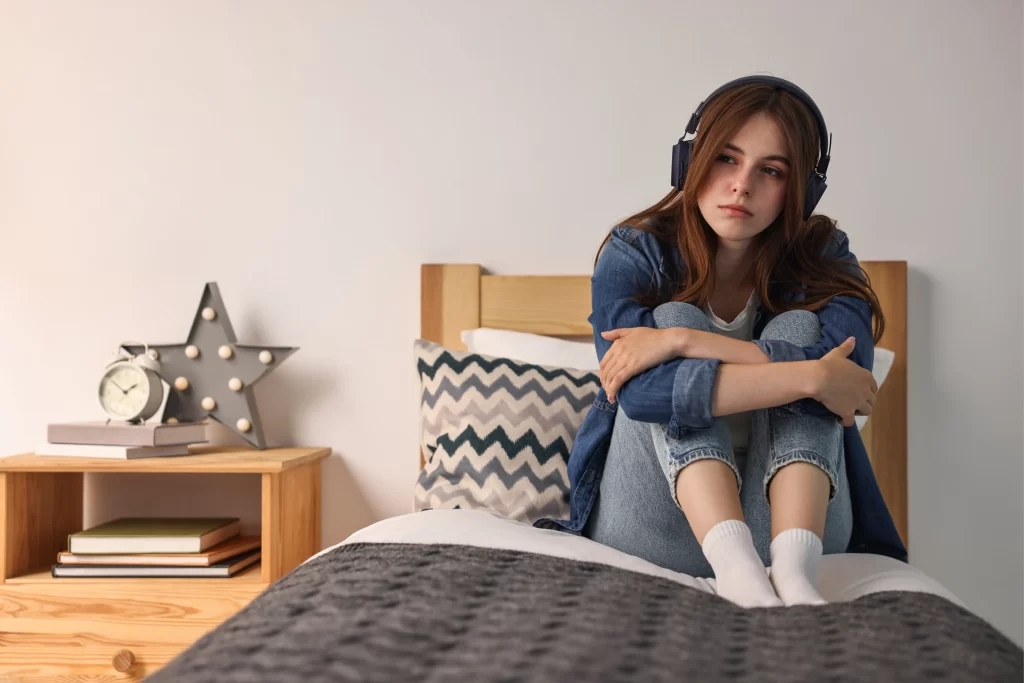 Vypořádat s problémy se lze různými způsoby. Zdroj: Shutterstock - ByznysDeník Chlapec se sluchátky sedící na posteli.