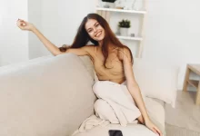 Žena sedí na sedačce a usmívá se.