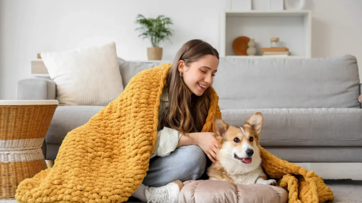 Žena leží v obývacím pokoji pod dekou s labradorem