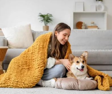Žena leží v obývacím pokoji pod dekou s labradorem