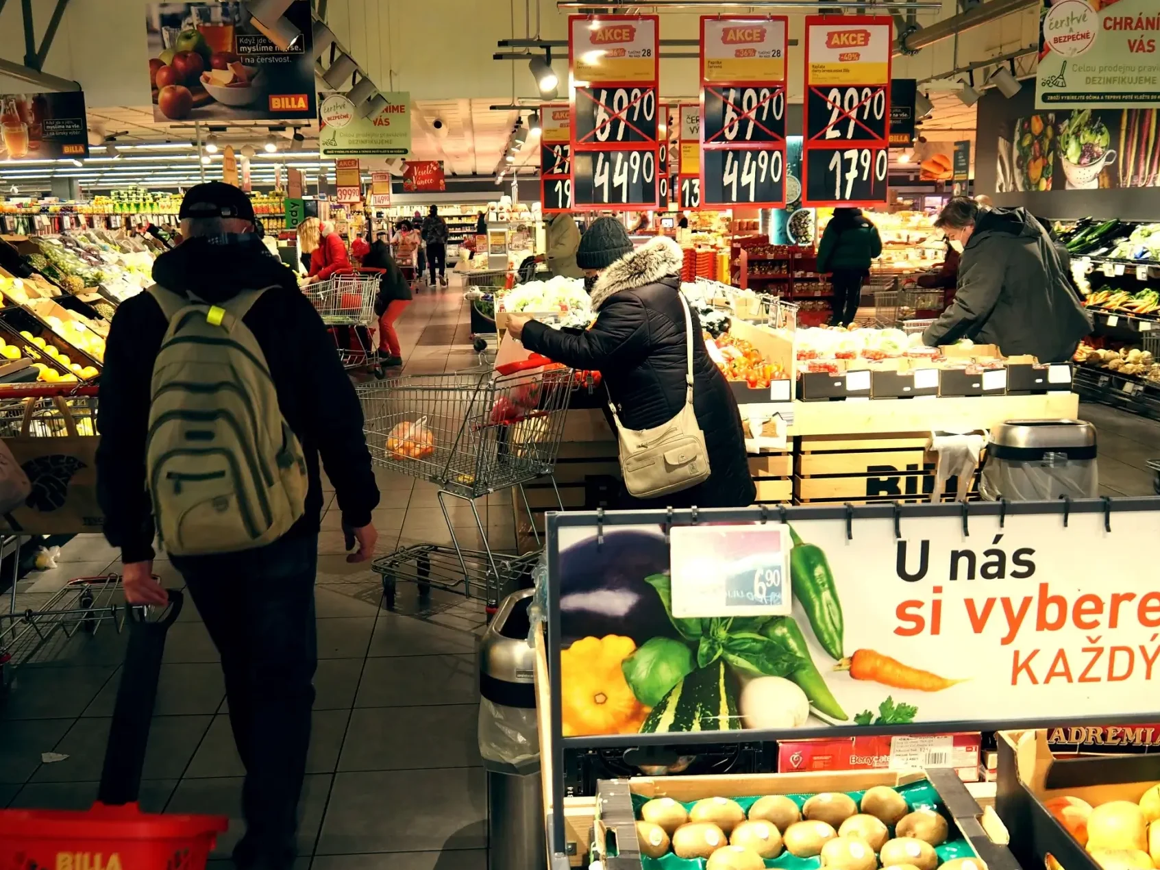 Uvnitř supermarketu prochází tákazníci oddělením ovoce a zeleniny