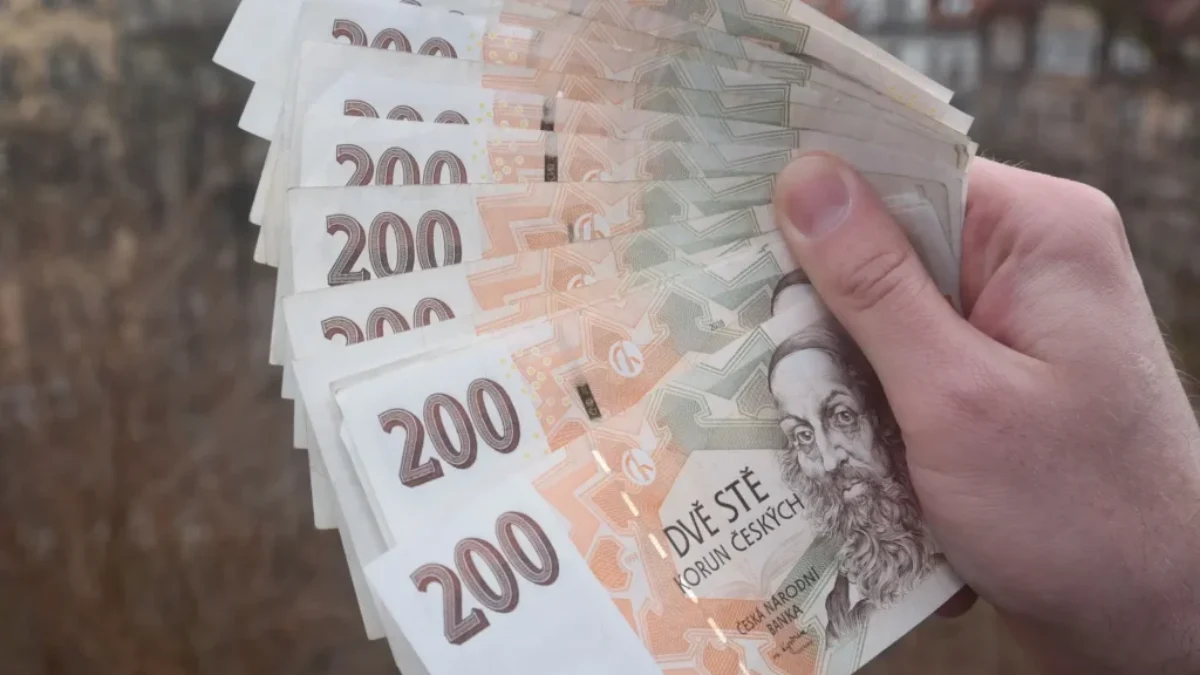 Ruka držící vějíř z několika českých bankovek v hodnotě 200 korun.