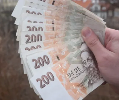 Ruka držící vějíř z několika českých bankovek v hodnotě 200 korun.