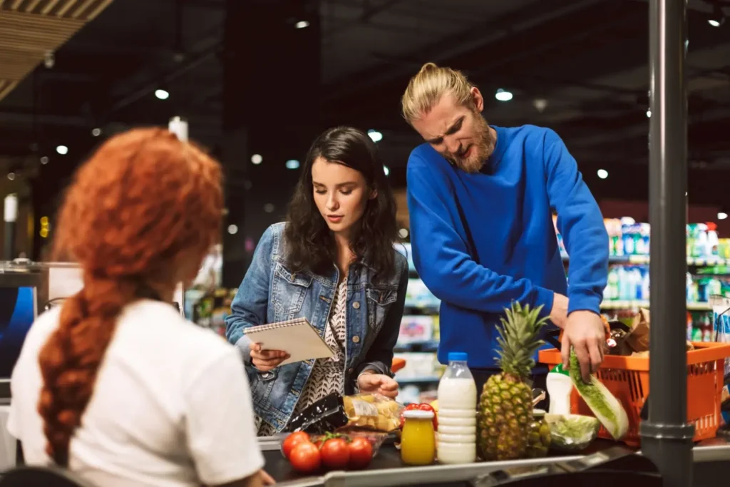 - ByznysDeník Mladý pár u pokladny diskutuje s prodavačkou v supermarketu