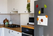 Kuchyňská linka s lednicí ozdobenou magnety ve tvaru listů a dětským obrázkem