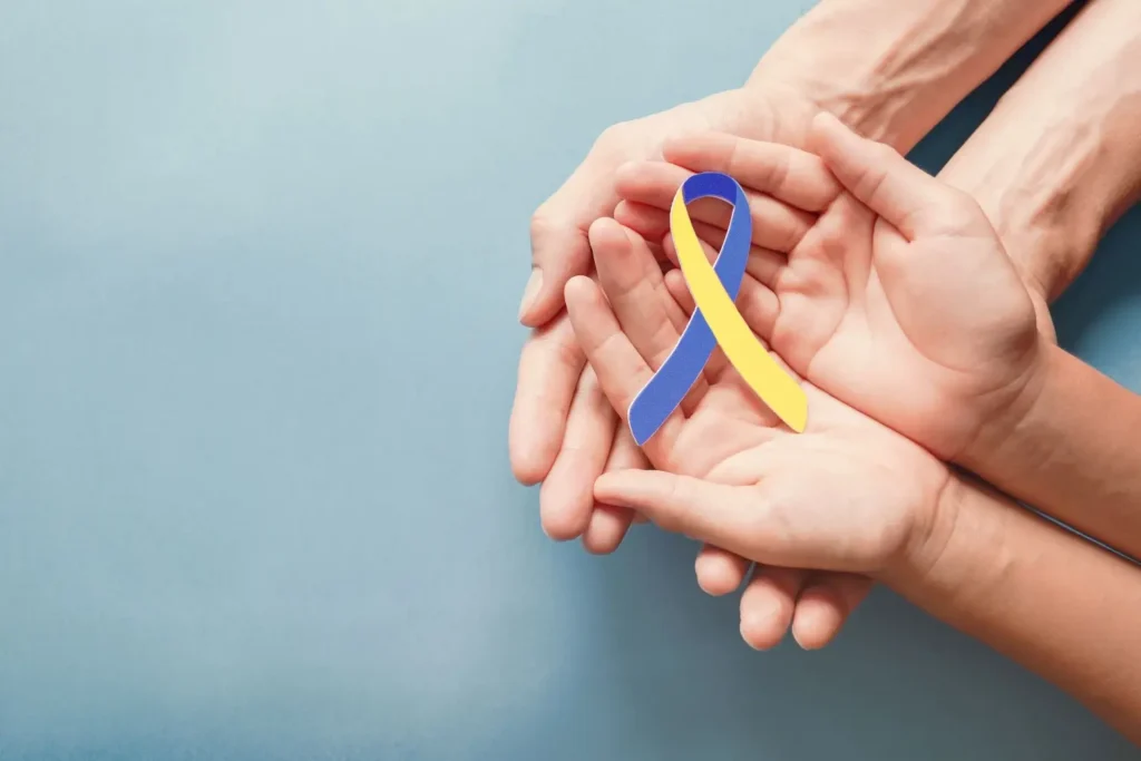 Dětská a dospělá ruka držící stužku ve žlutomodré barvě 