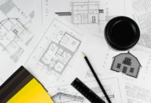 Detail stavebních výkresů a plánů s tužkou, pravítkem a kelímkem kávy