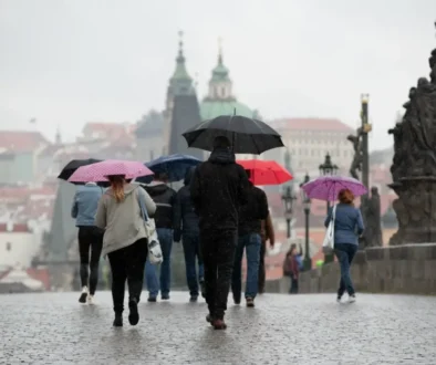 Skupina lidí s barevnými deštníky přechází Karlův most v Praze