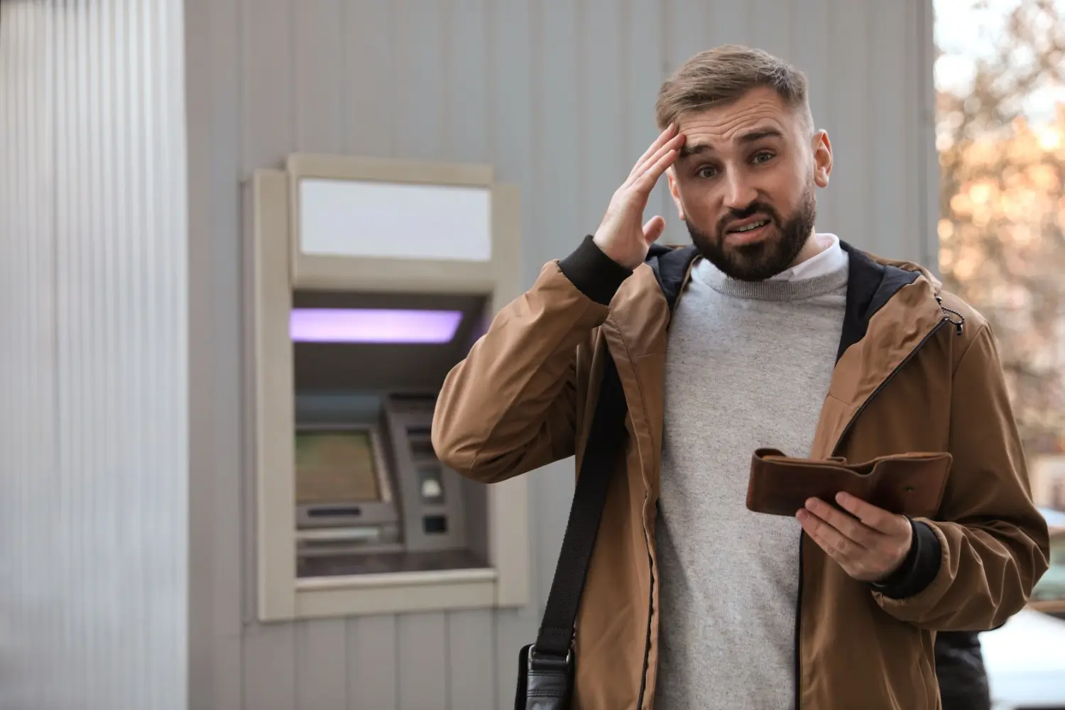 Muž u bankomatu s prázdnou peněženkou