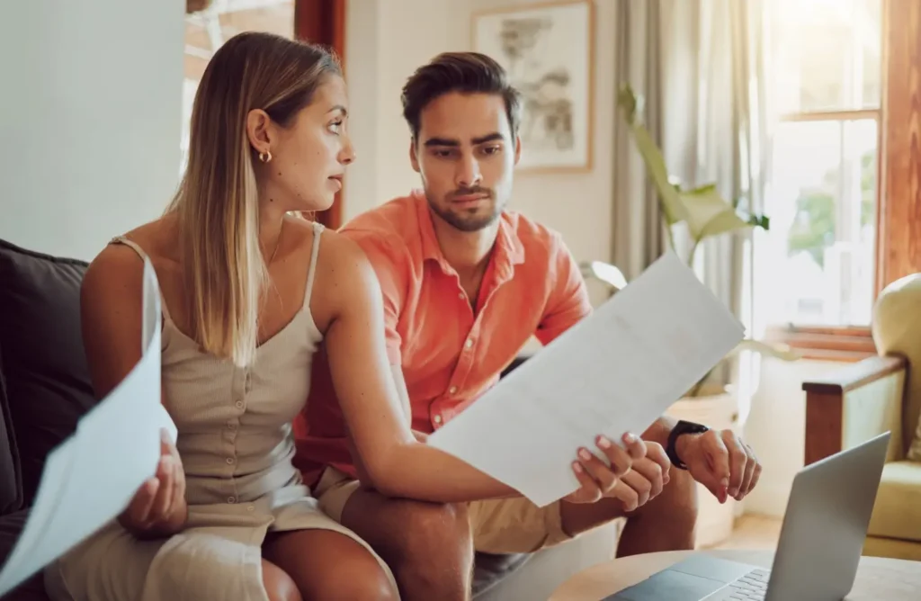 Pár sedí na gauči a společně probírá domácí finance s vážnými výrazy