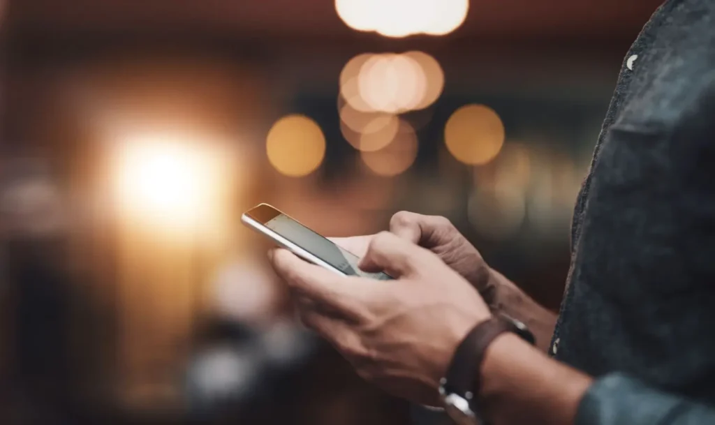 Detail rukou muže, který píše na chytrém telefonu