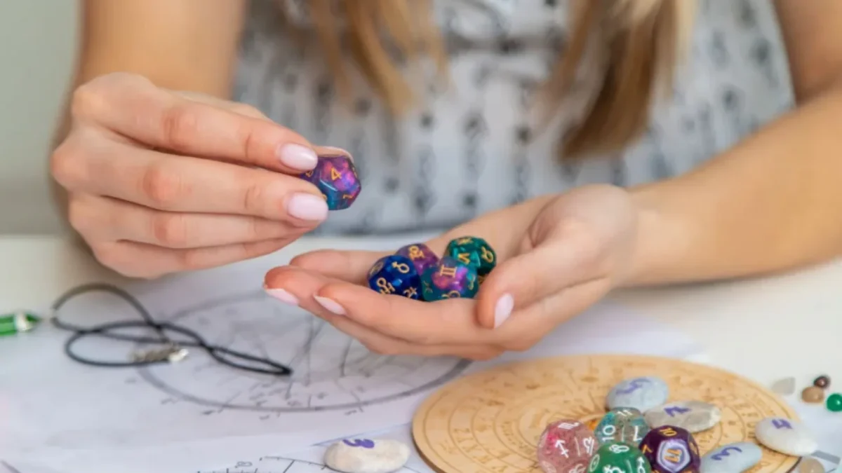 Žena drží astrologické kostky nad horoskopickým kolem na stole