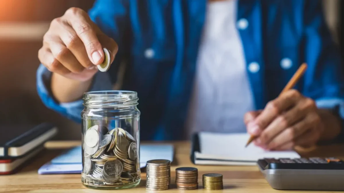 Muž sype peníze do sklenice