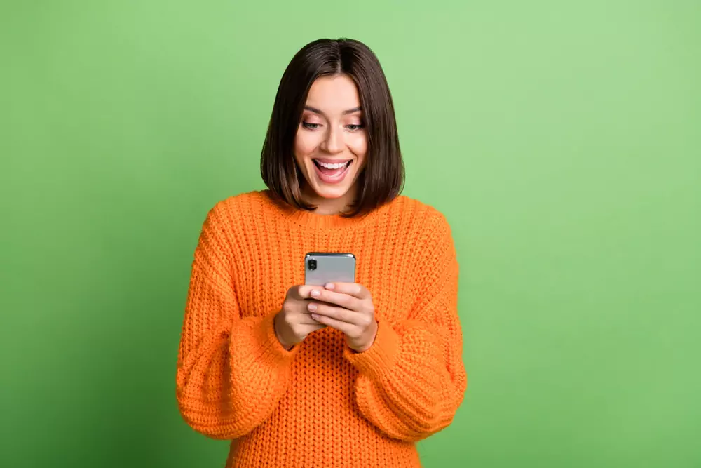 žena koukající do telefonu s nadšeným výrazem