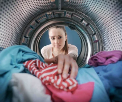 Dívka dává prádlo do pračky