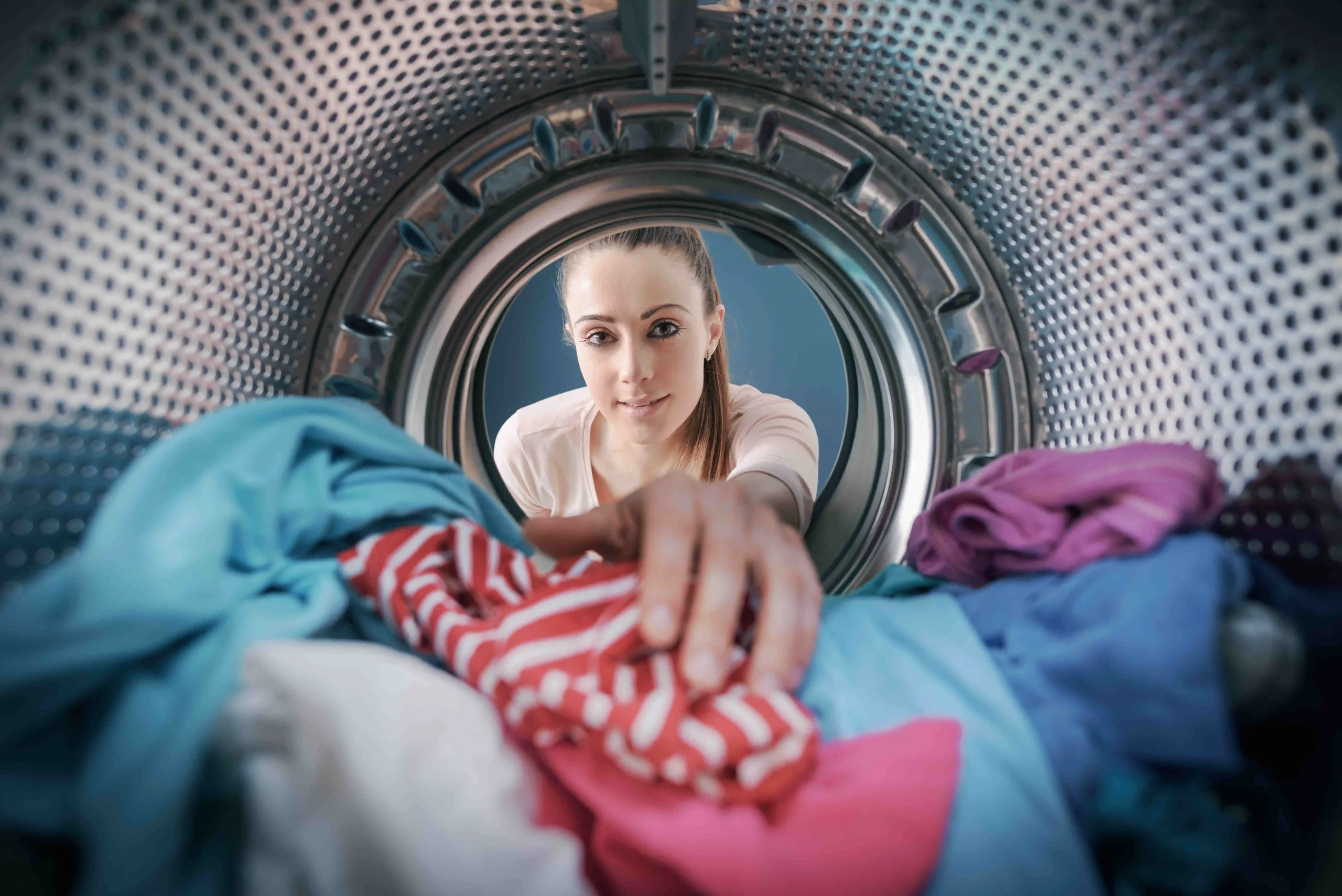 Dívka dává prádlo do pračky
