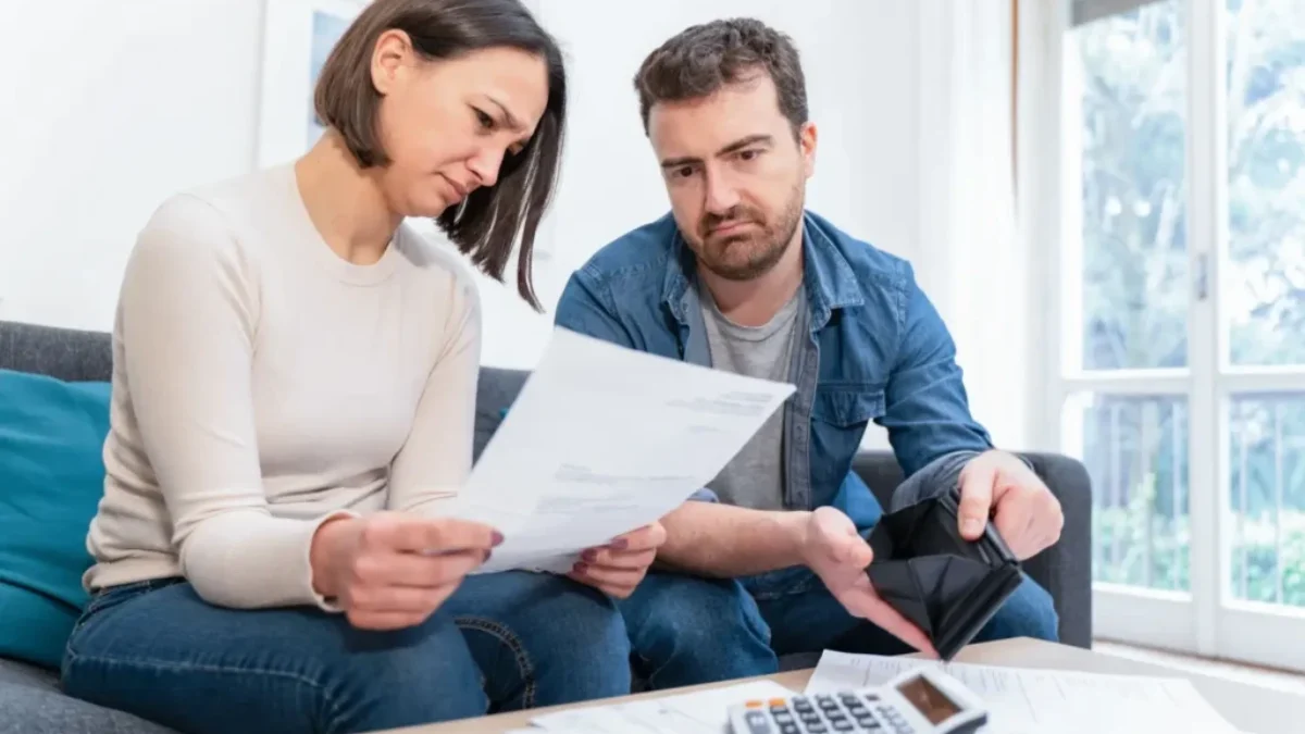 Muž a žena doma procházejí účty a přemýšlejí, jak zvládnout rostoucí náklady