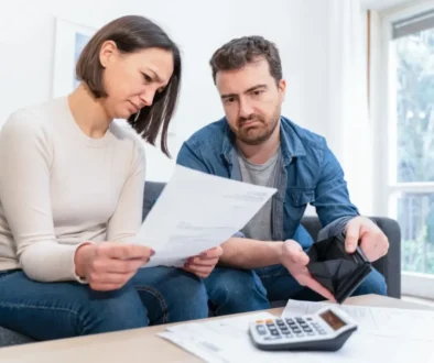 Muž a žena doma procházejí účty a přemýšlejí, jak zvládnout rostoucí náklady