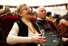 Starší žena se baví při divadelním představení a vedle ní sedí další diváci