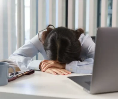 Žena sedící u pracovního stolu s hlavou položenou na rukách