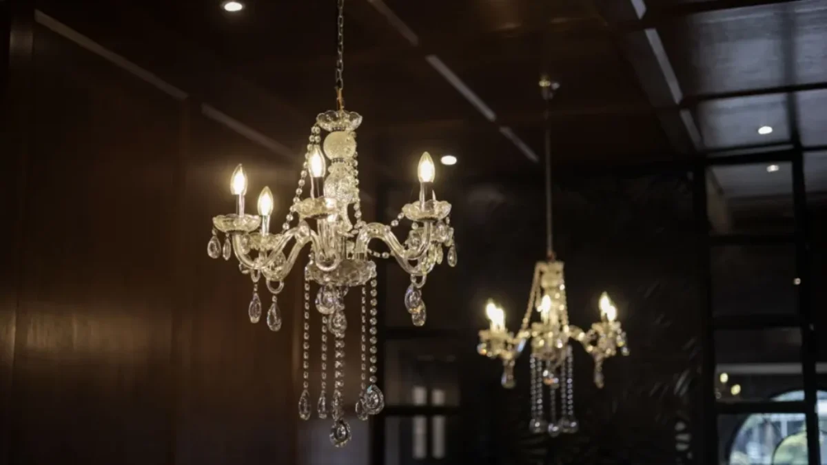 Historický křišťálový lustr se skleněnými kapkami zavěšený v interiéru s dřevěným stropem