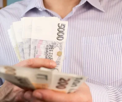 Muž v košili držící několik českých bankovek