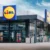 Pohled na vstupní část moderní prodejny Lidl s velkým logem a skleněnou fasádou