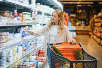 ena s nákupním košíkem vybírá zboží v chladicím regálu