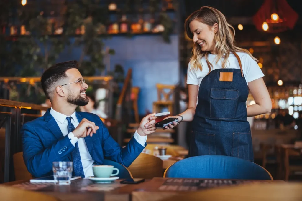 Muž platí kartou v restauraci servírce s mobilním terminálem