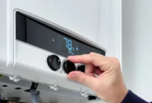 Ruka otáčí regulačním kolečkem na moderním bojleru