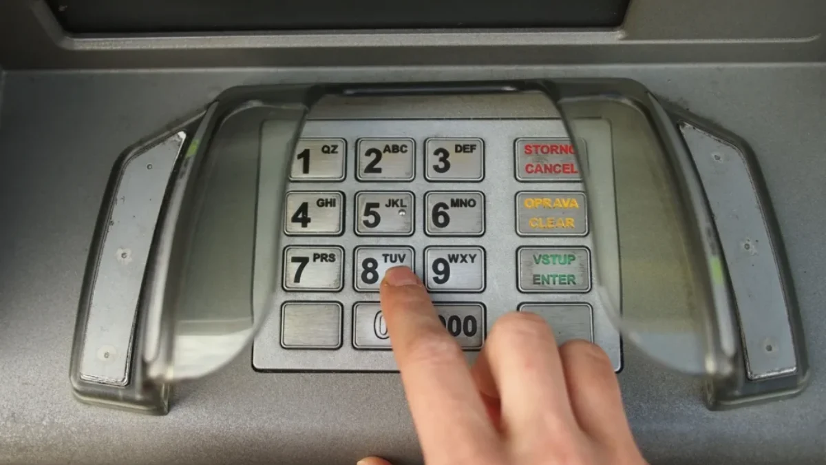 Ruka zadává PIN na bankomatu