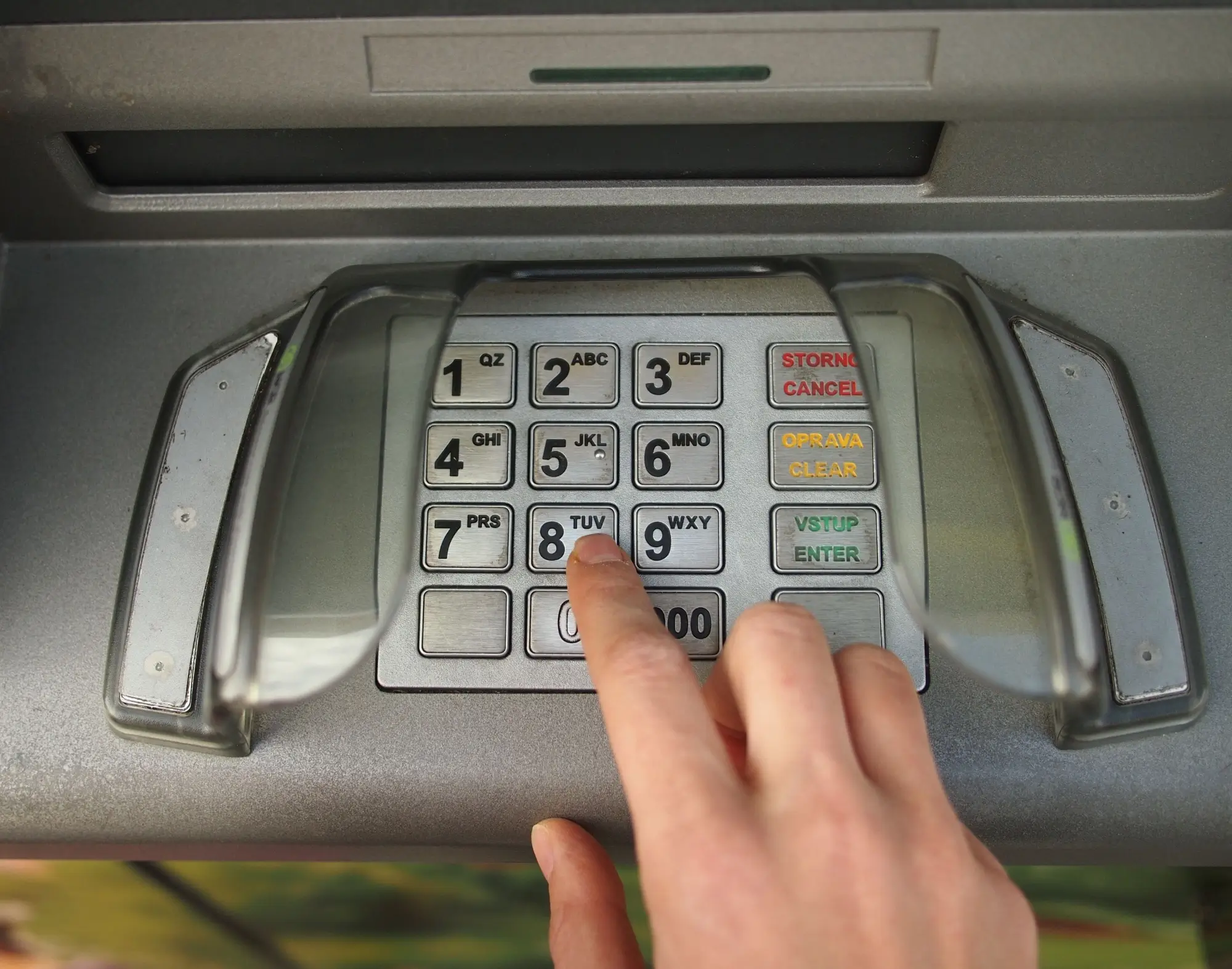 Ruka zadává PIN na bankomatu