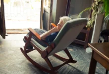 Stará paní sedí v křesle a dívá se z otevřeného okna